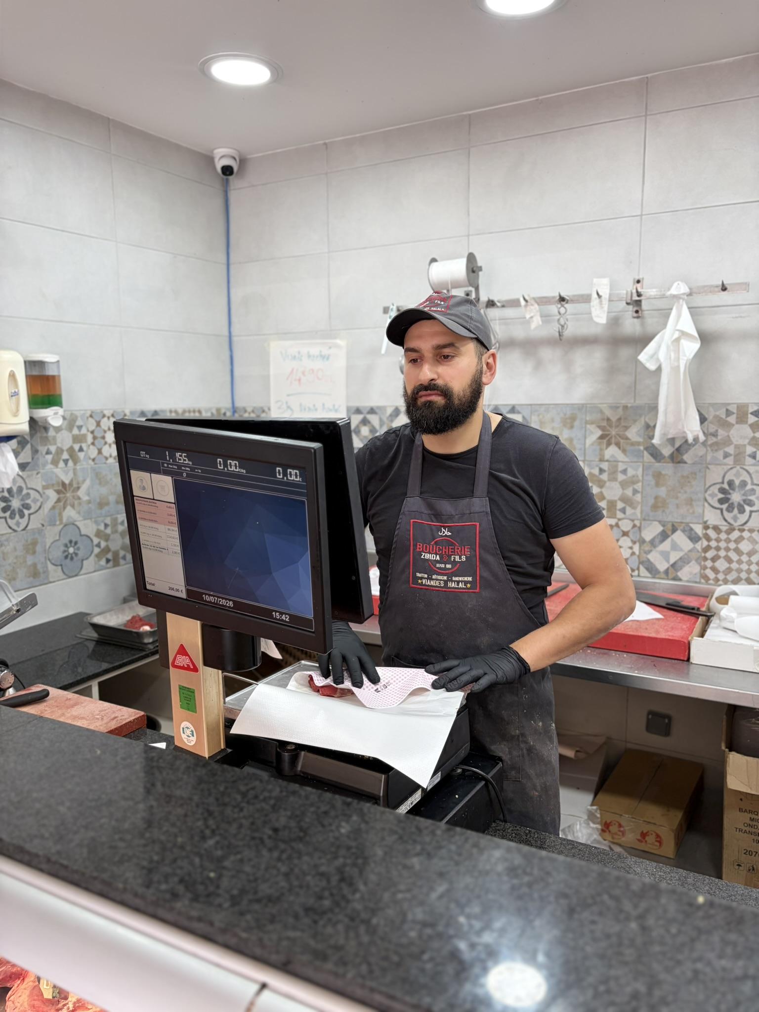 Le boucher pèse et emballe une pièce de viande au comptoir